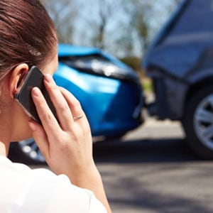 Female on phone inspecting car post-accident - Levian Law
