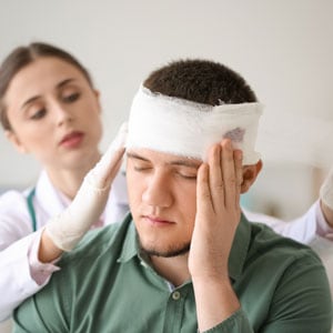 A woman holding the head of a man with bandages, representing a brain injury - Levian Law