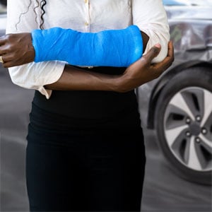 An injured woman beside a damaged car, indicating a car accident